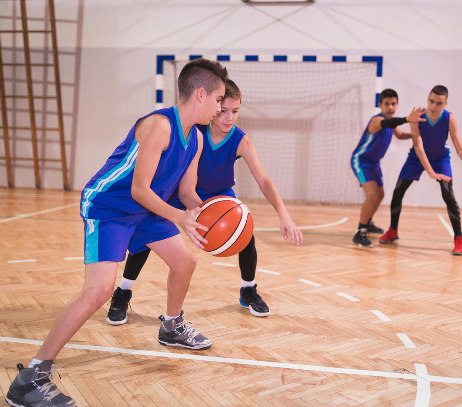 Boys playing basketball in a school gym.
